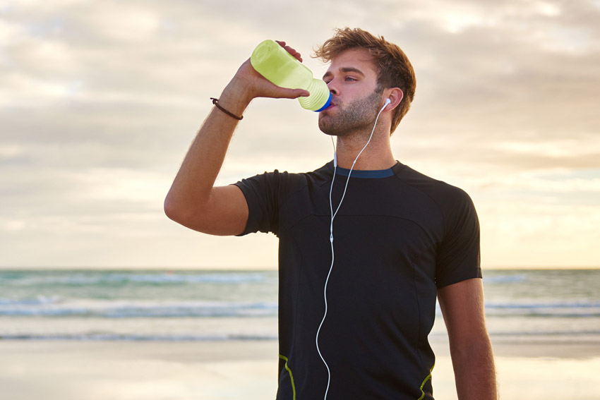 Young athletic man drinks a Lime KSP tab from a water bottle.