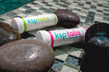 A berry and lime KSP tab tube sits on tile with shiny stones.