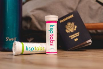 A tube of berry and lime KSP tabs sits next to a passport.