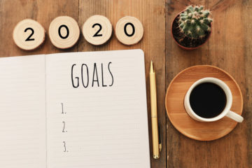 A calendar showing goals for 2020 next to a cup of coffee.