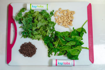 A cutting board with Lime and Berry KSP tabs next to Kale, Spinach, and Nuts.
