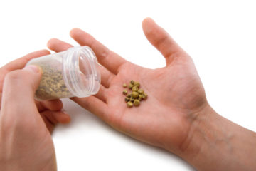 A man pours small stones from a plastic jar into his hand.