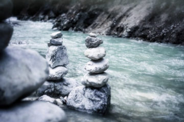 Stones stacked on top of each other in front of a river.