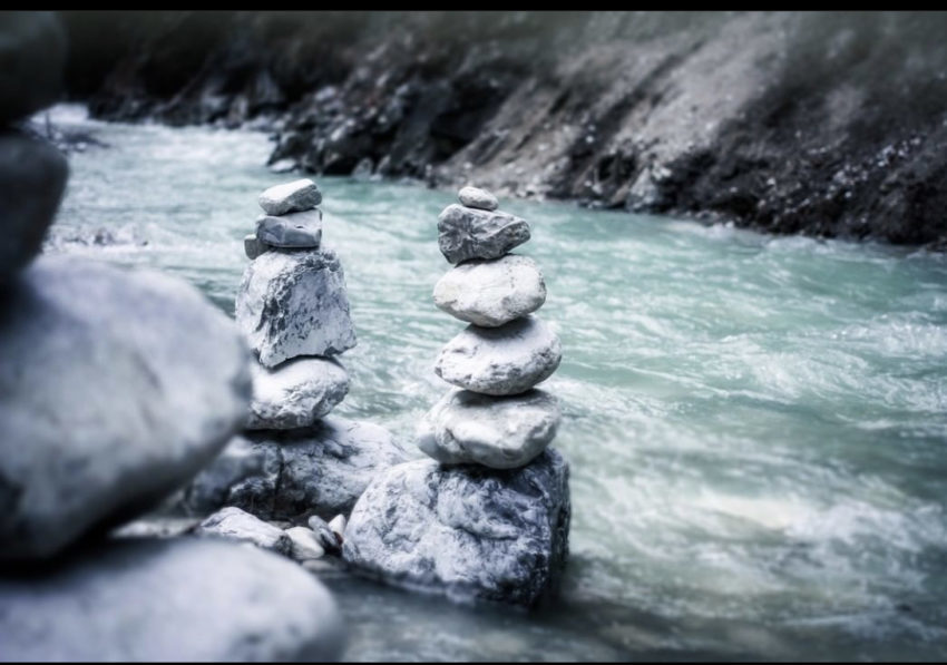 Stones stacked on top of each other in front of a river.